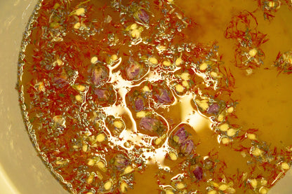 Close-up of botanical ingredients infusing in warm water during a herbal foot soak, showing floating petals and natural plant textures.