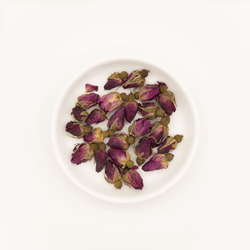 Rosa rugosa buds/flowers (Rosa rugosa) – Chinese traditional medicine (TCM) herb in white ceramic dish, flat lay white background studio photograph