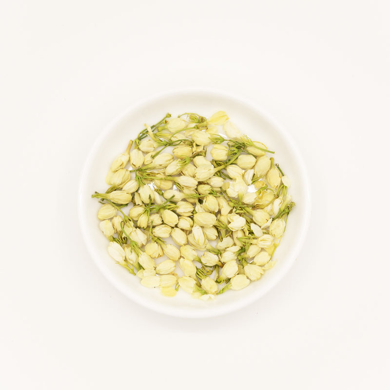 Jasmine Flower (Jasminum sambac) – Chinese traditional medicine (TCM) herb in white ceramic dish, white background flat lay studio photograph